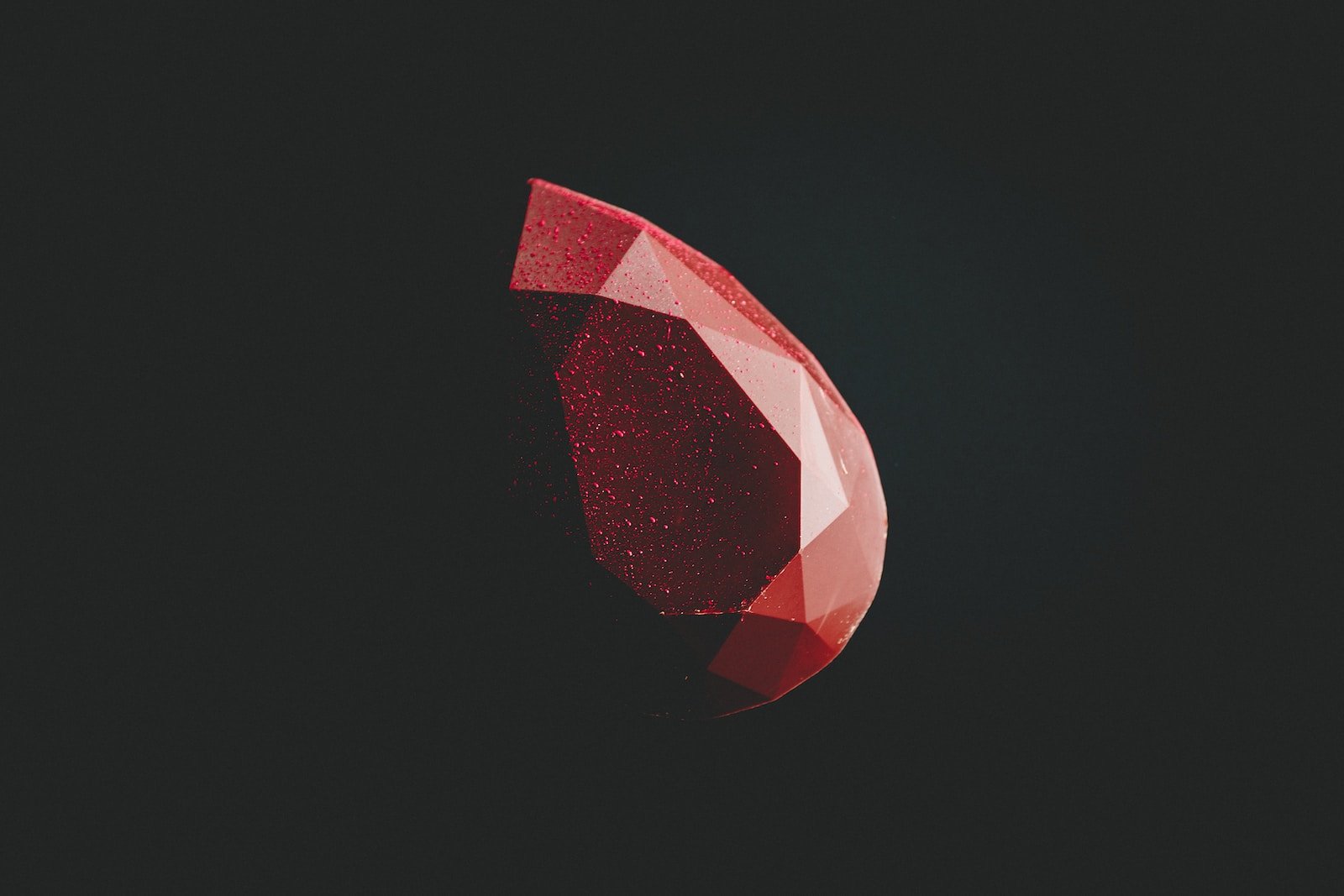 selective focus photography of faceted red gemstone